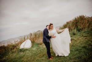 Les mariés dans les dunes, la mariée tient la traine de sa robe