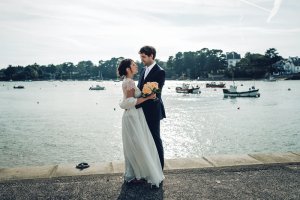 La mariée en robe et le marié devant la mer