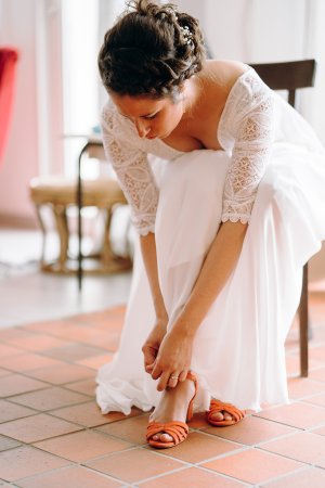 La mariée en robe sur mesure remet sa chaussure