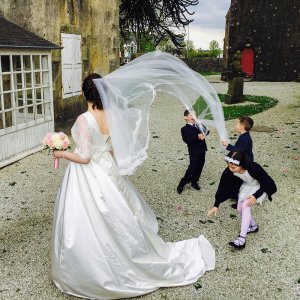 Typhaine en robe de mariée, des enfants jouent avec son voile et sa traine